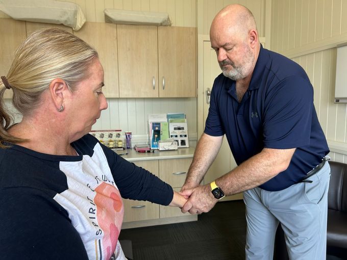 Woman in Blue Top Examines a Person's Leg on a Medical Table — Wide Bay Chiropractic in Gympie, QLD