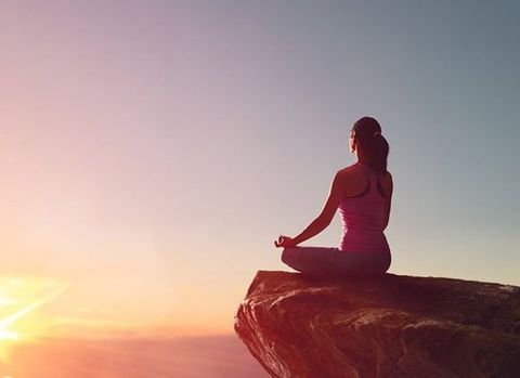 Woman in Yoga Pose Atop a Cliff at Sunset — Wide Bay Chiropractic in Gympie, QLD