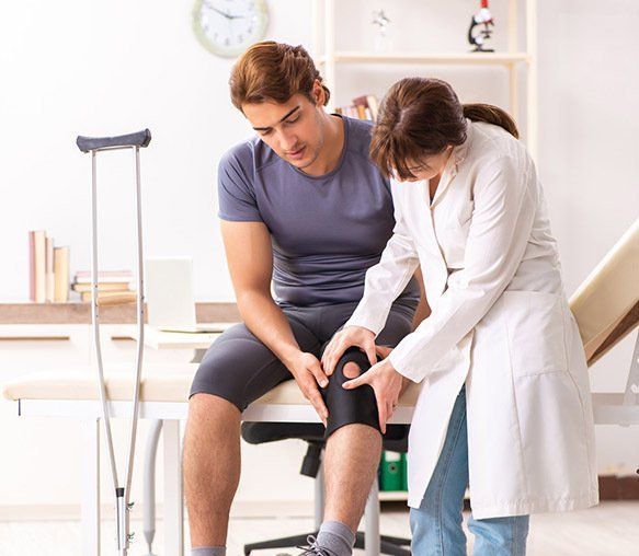 Doctor Examining Patient's Injured Knee — Wide Bay Chiropractic in Gympie, QLD