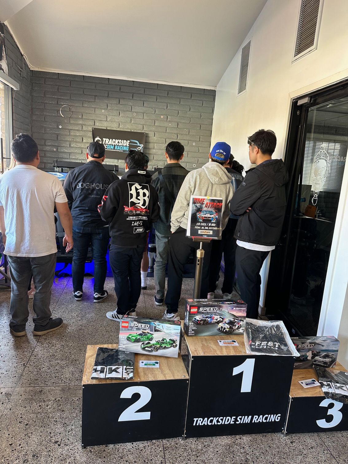 People viewing racing merchandise, numbered podium display, shop interior.