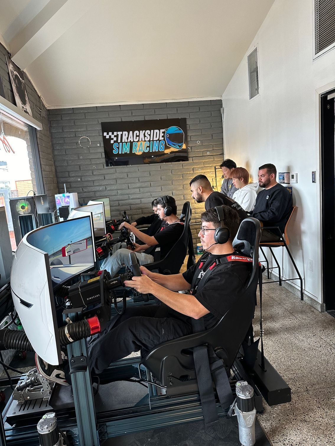 People using racing simulator setups. Interior shot.