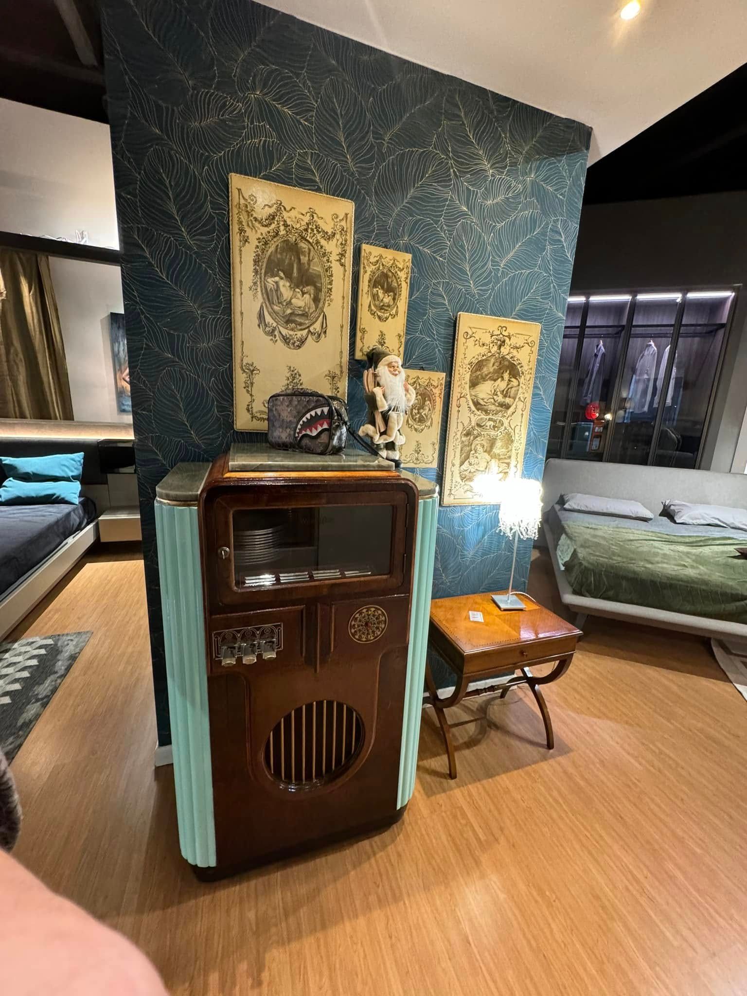 Un mobile radio in stile antico con opere d'arte, un tavolino e un letto in uno showroom.