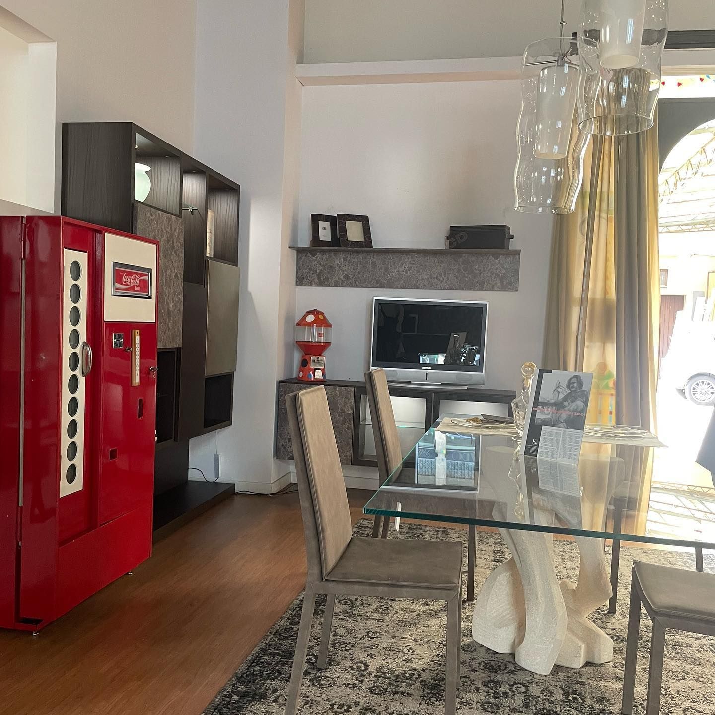 Una sala da pranzo con tavolo, sedie e un distributore automatico. La TV è appoggiata su un mobile.