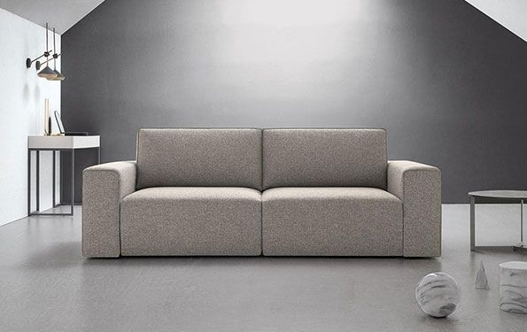 Divano beige a due posti contro una parete grigia. Tavolini e complementi d'arredo completano l'ambiente moderno del soggiorno.