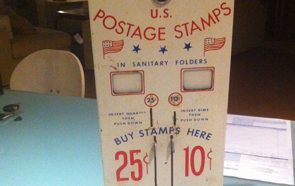 Distributore automatico di francobolli d'epoca degli Stati Uniti, bianco con testo e bandiere rossi/blu, per francobolli da 25 centesimi e 10 centesimi.