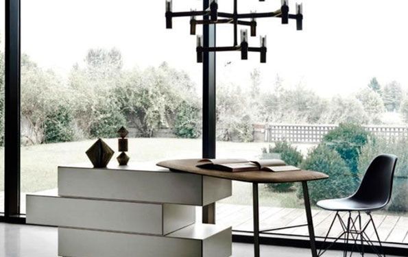 Ufficio moderno con scrivania, sedia e lampadario con vista su un tranquillo cortile.