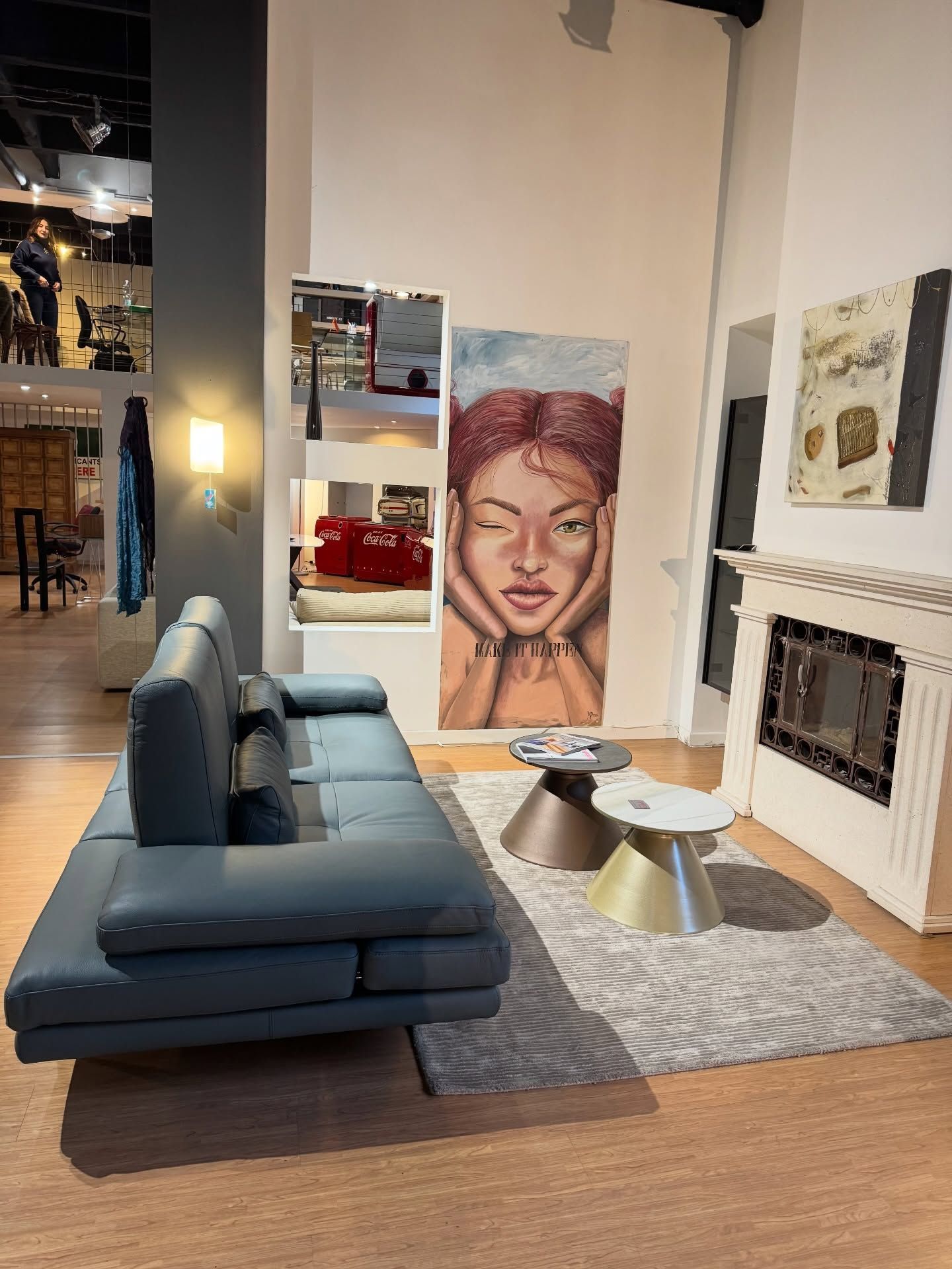 Soggiorno moderno con divano blu, opere d'arte e camino.