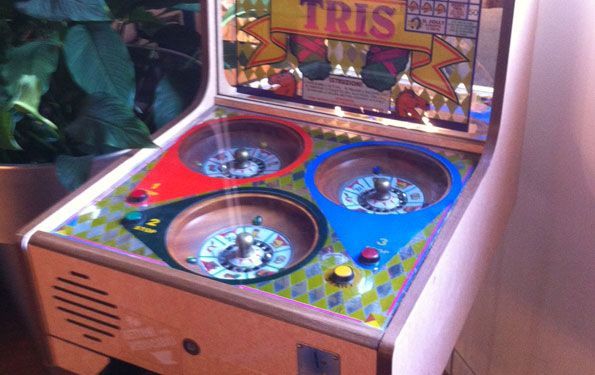 Videogioco arcade con tre ruote rotanti, colorate di rosso, blu e verde. 