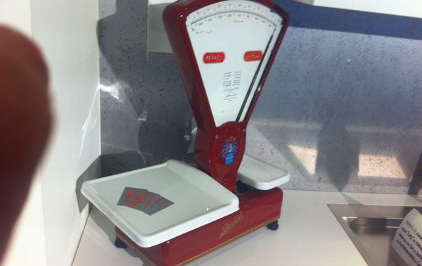 Bilancia vintage rossa e bianca su una superficie bianca con sfondo grigio.