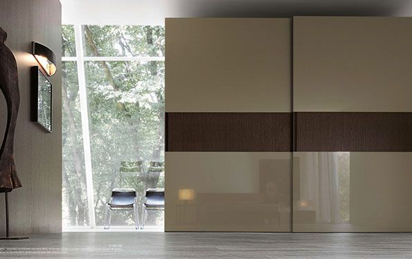 Porte scorrevoli beige e marroni per armadi in una stanza moderna con una grande finestra e opere d'arte.