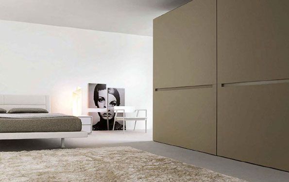 Camera da letto con un ampio armadio, un letto, un'opera d'arte e un soffice tappeto in una tavolozza di colori neutri.