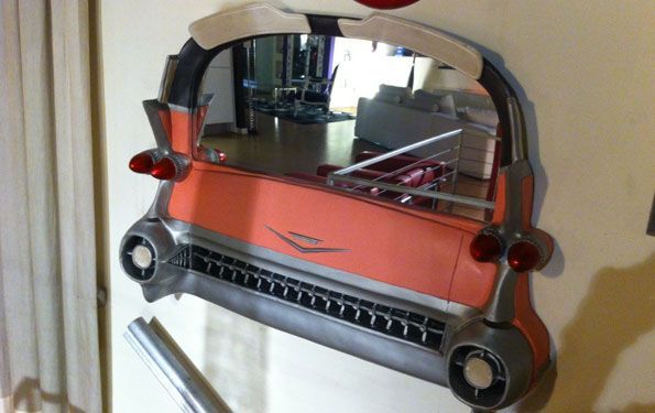 Specchio a forma di posteriore di un'auto d'epoca rosa. Dettagli argento e neri, montato a parete.