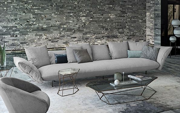 Soggiorno moderno con divano grigio e parete in pietra.