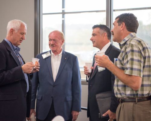 A group of men are standing next to each other in a room talking.
