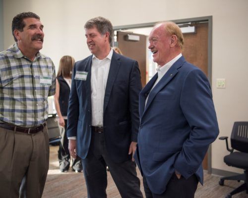 Three men in suits are standing next to each other and laughing