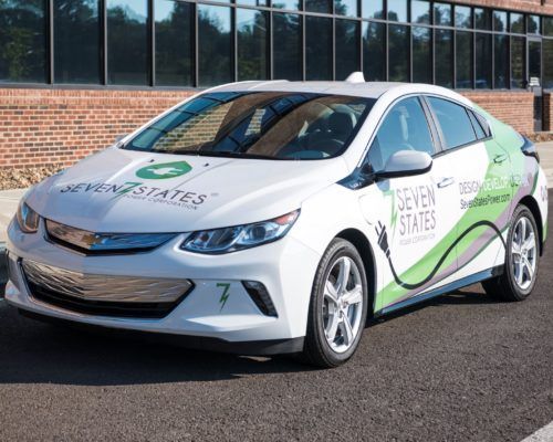 A seven states electric car is parked in front of a building