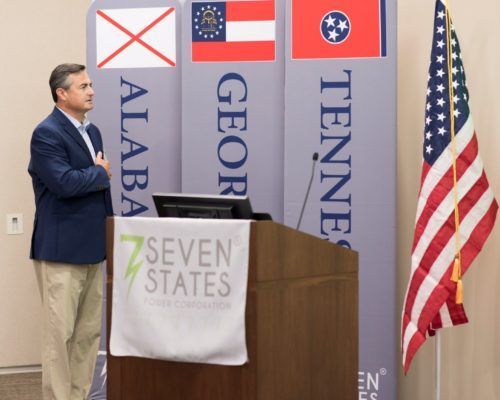 A man stands behind a podium that says seven states