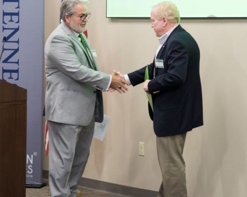 Two men are shaking hands in front of a podium.