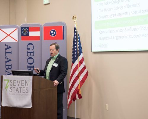 A man is standing at a podium with an american flag in front of him.