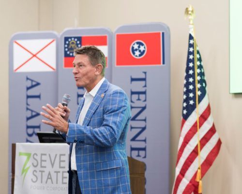 A man stands behind a podium that says seven state