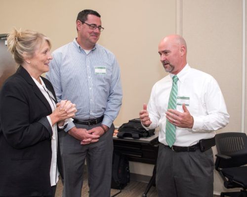 Two men and a woman are talking to each other in a room