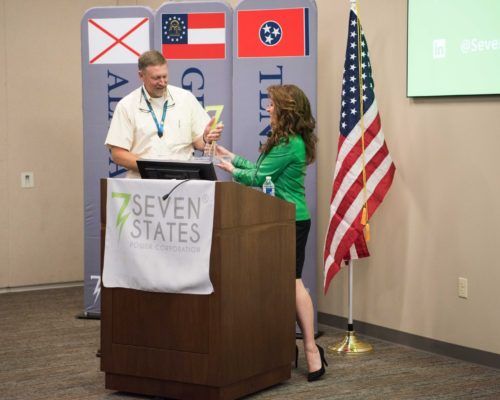 A woman stands behind a podium that says seven states