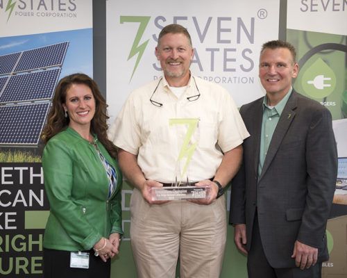 A man and two women are standing next to each other holding a trophy.