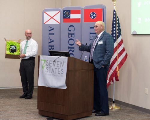 A man stands behind a podium that says seven states