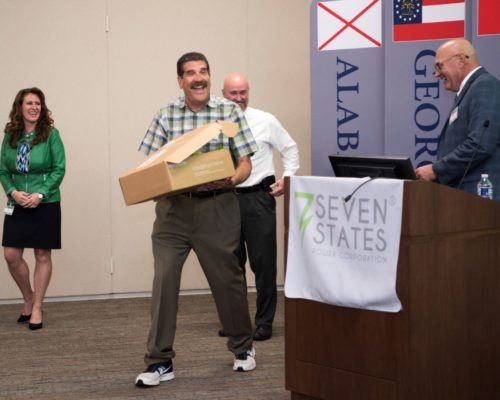 A man holding a box in front of a podium that says seven states
