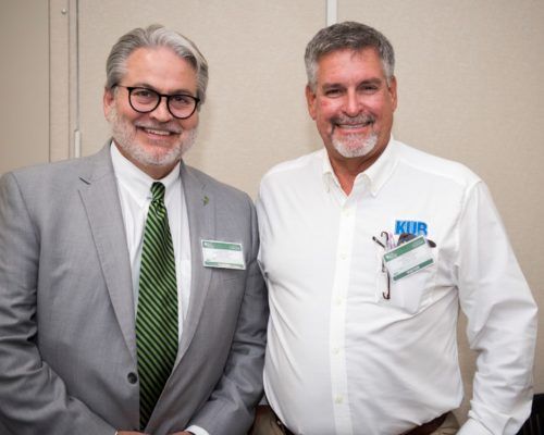 Two men in suits and ties are posing for a picture.