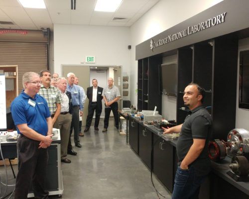 A group of men are standing in front of a sign that says scott national laboratory