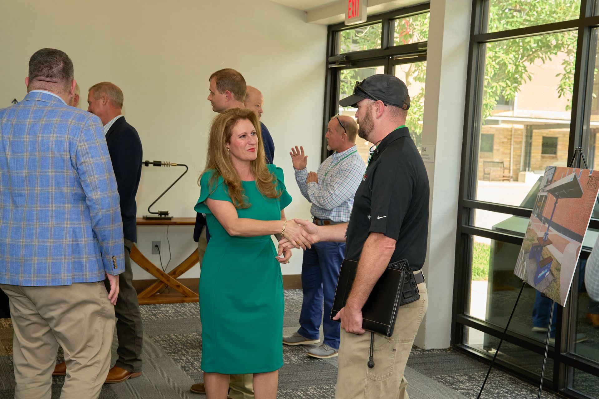 A woman in a green dress is shaking hands with a man in a black shirt.
