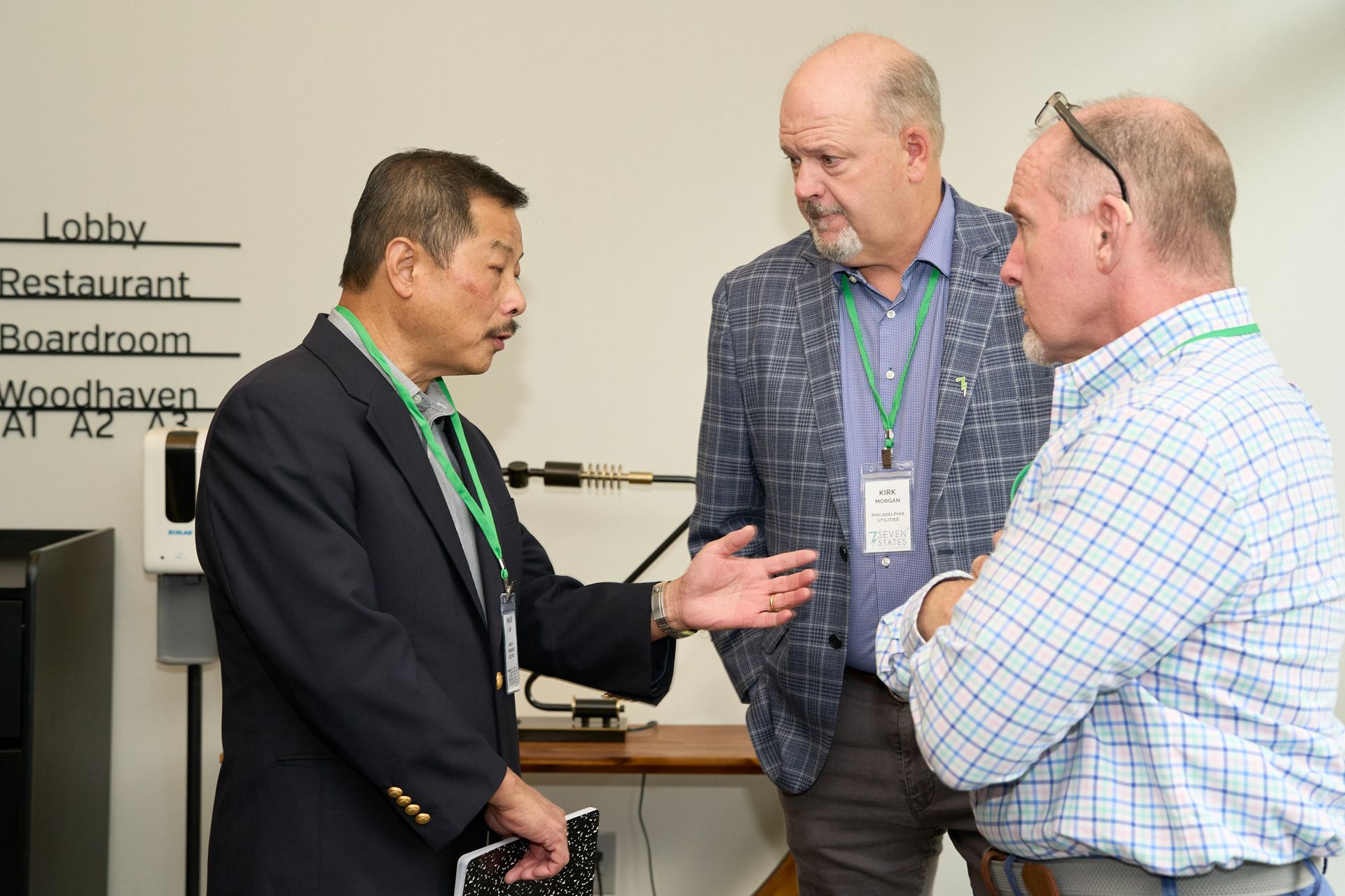 Three men are talking to each other in a room.