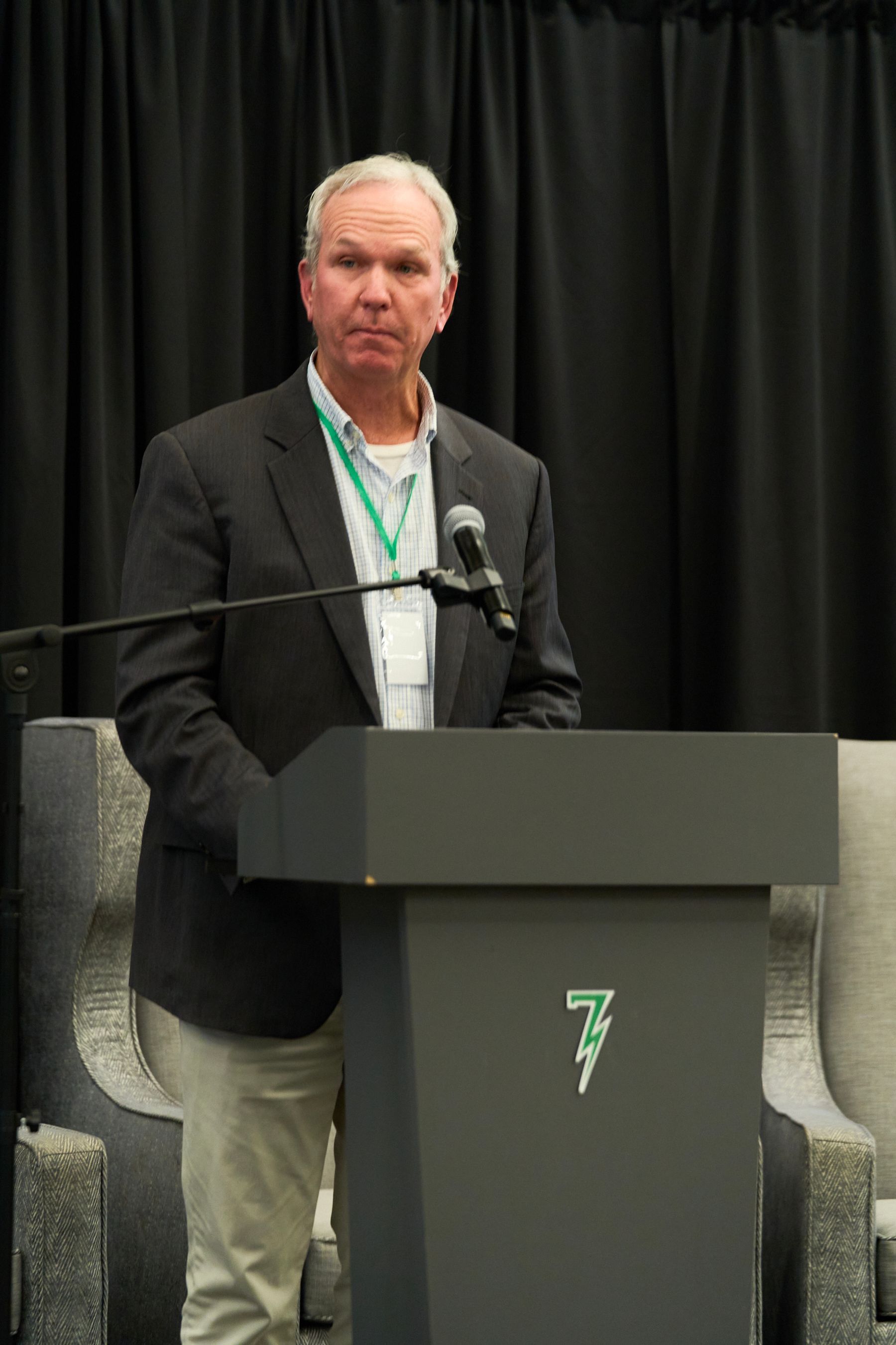 A man in a suit is standing at a podium with a microphone.