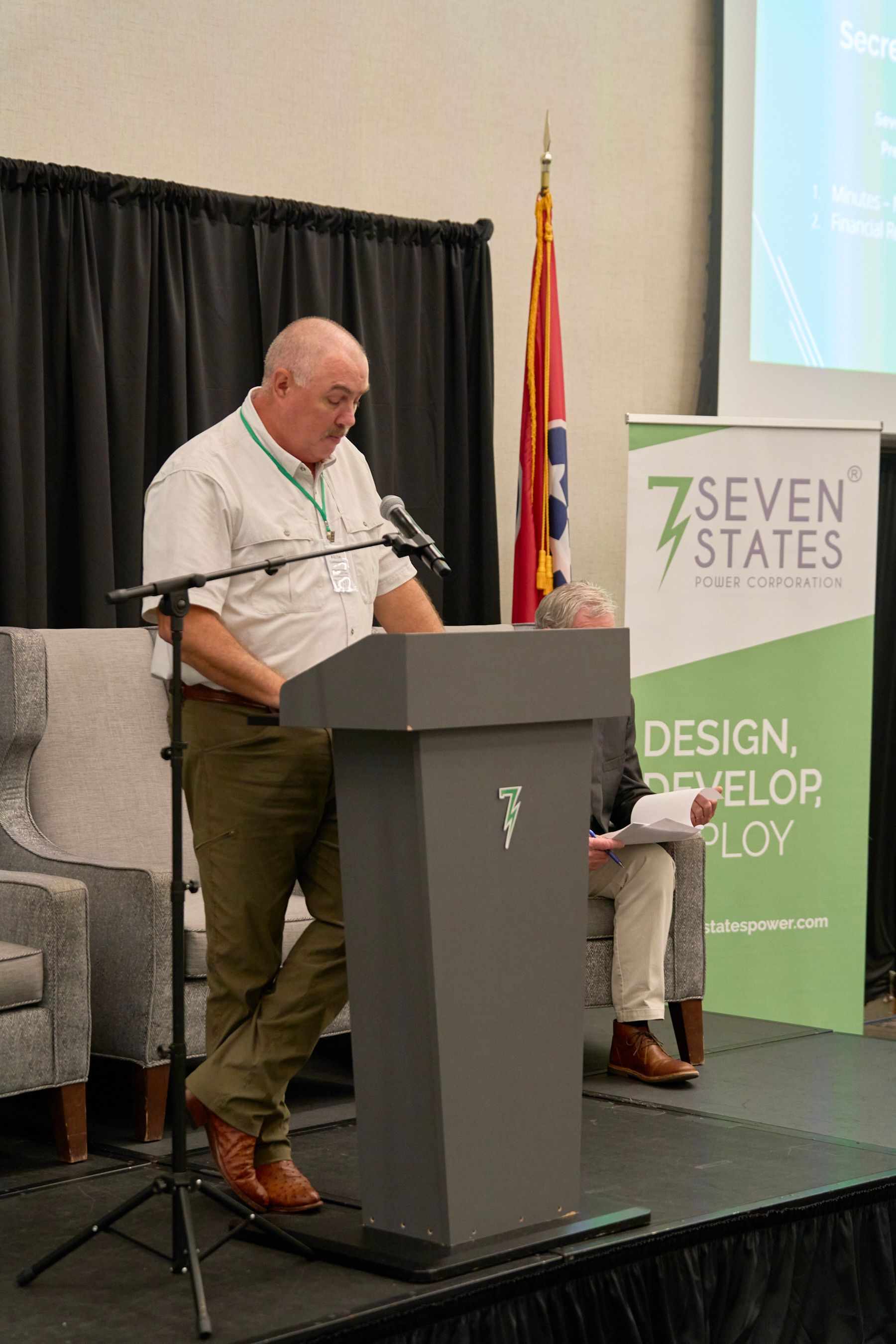 A man is standing at a podium speaking into a microphone.