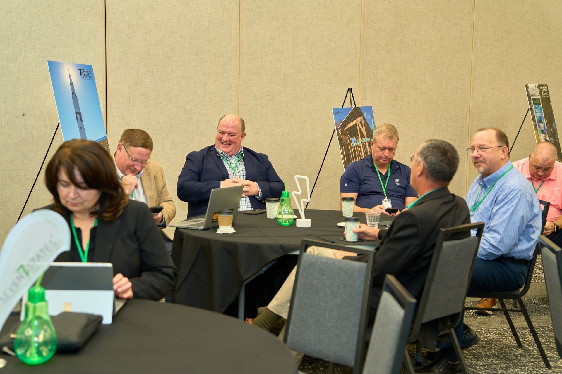A group of people are sitting around a table with laptops.