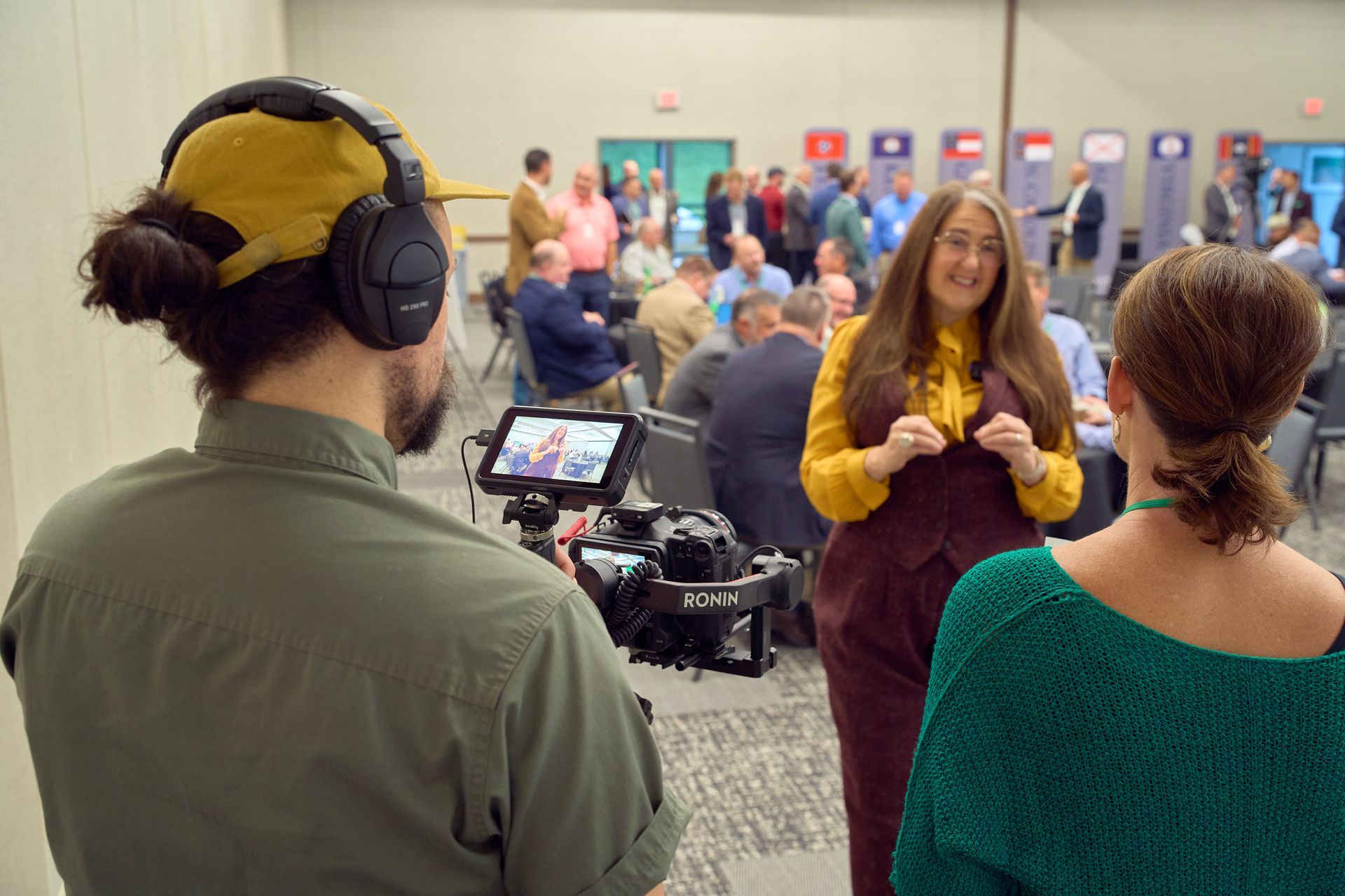 A man is recording a woman talking in front of a camera.
