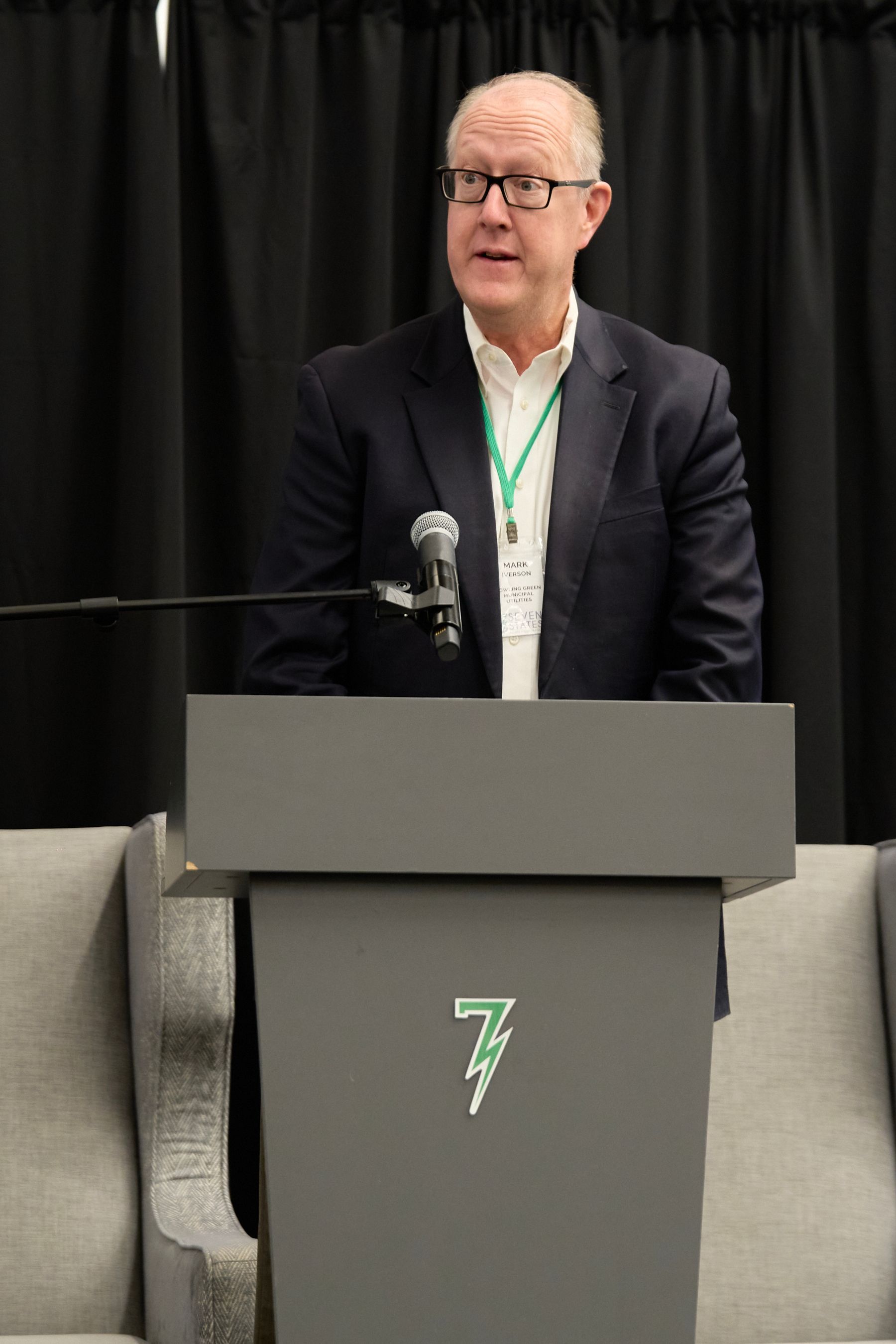 A man stands at a podium with a lightning bolt on it
