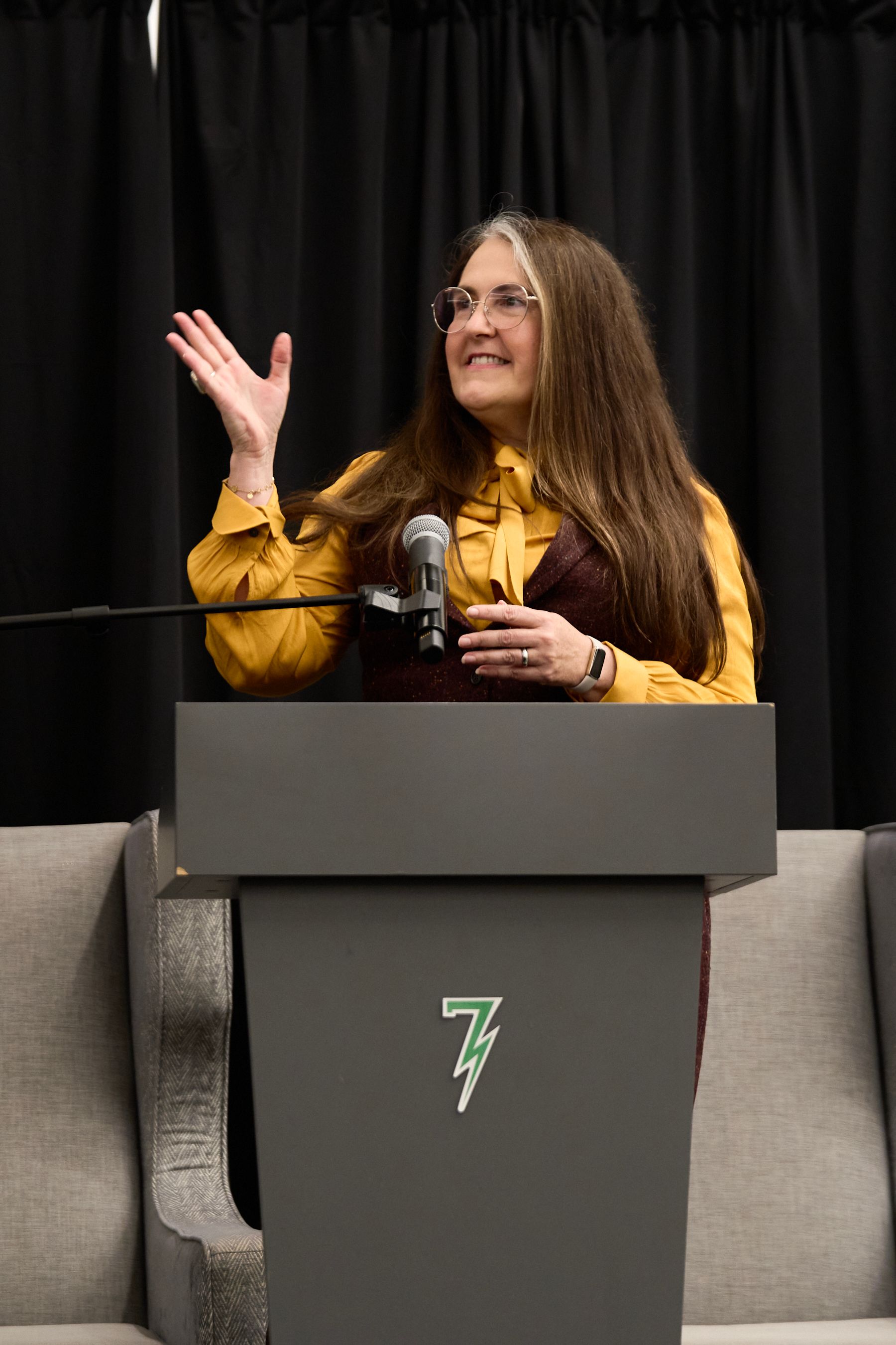 A woman is standing at a podium with a microphone.