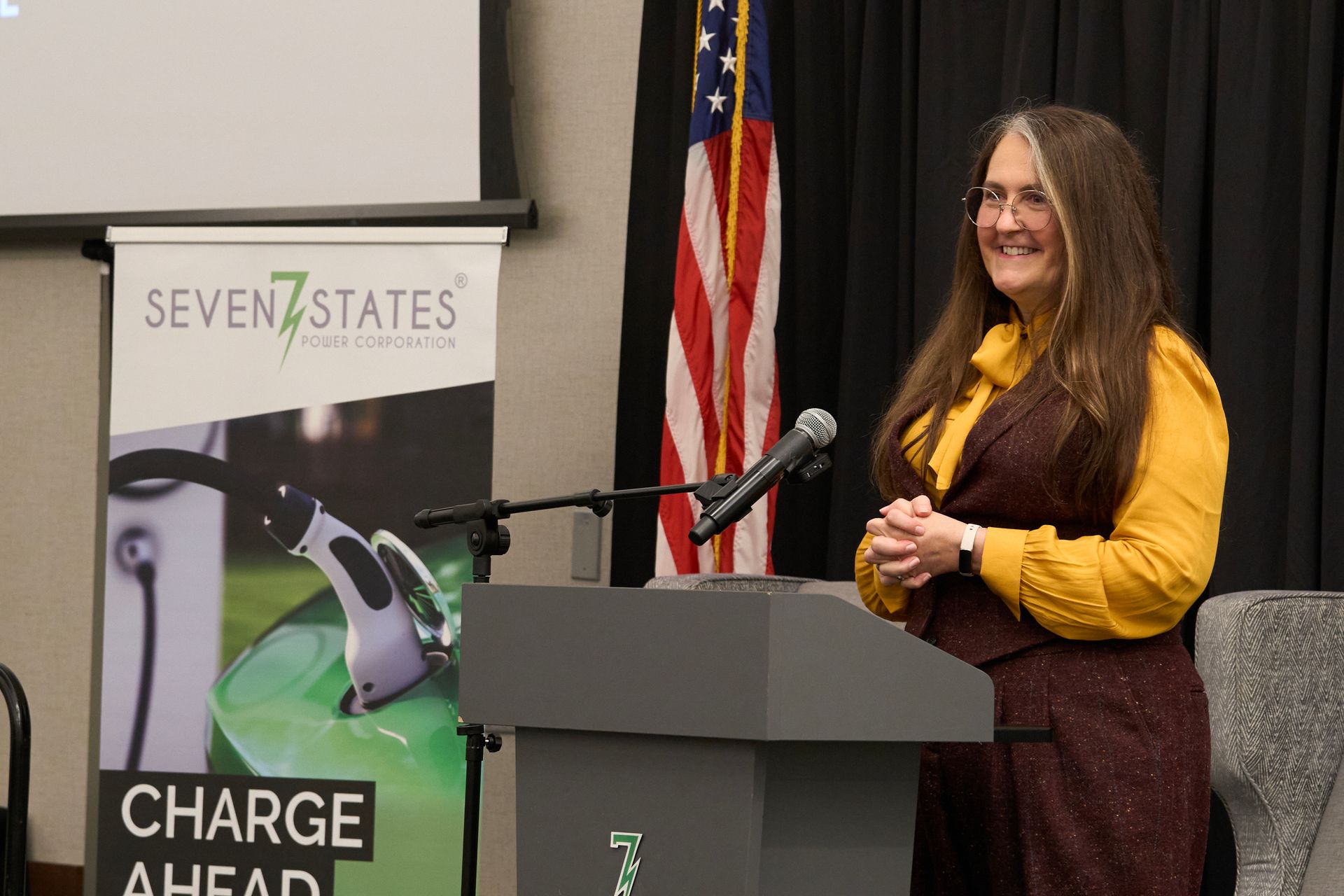 A woman is standing at a podium in front of a microphone.