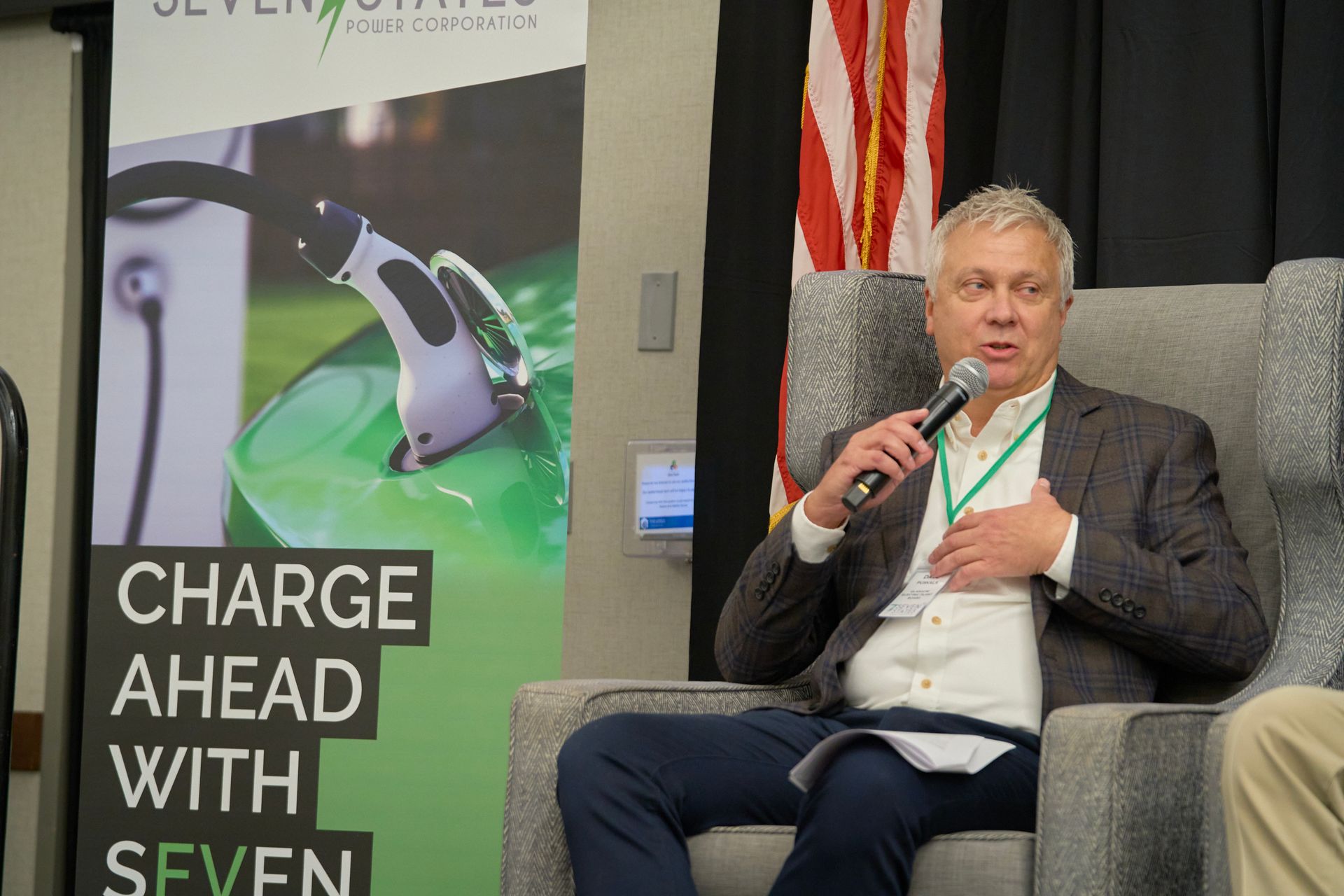 A man is sitting in a chair talking into a microphone.