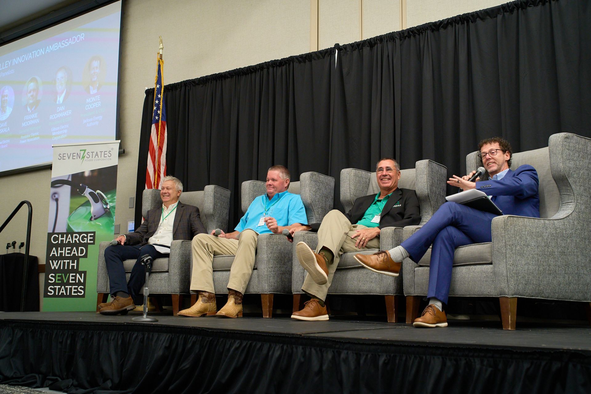 A group of men are sitting in chairs on a stage.