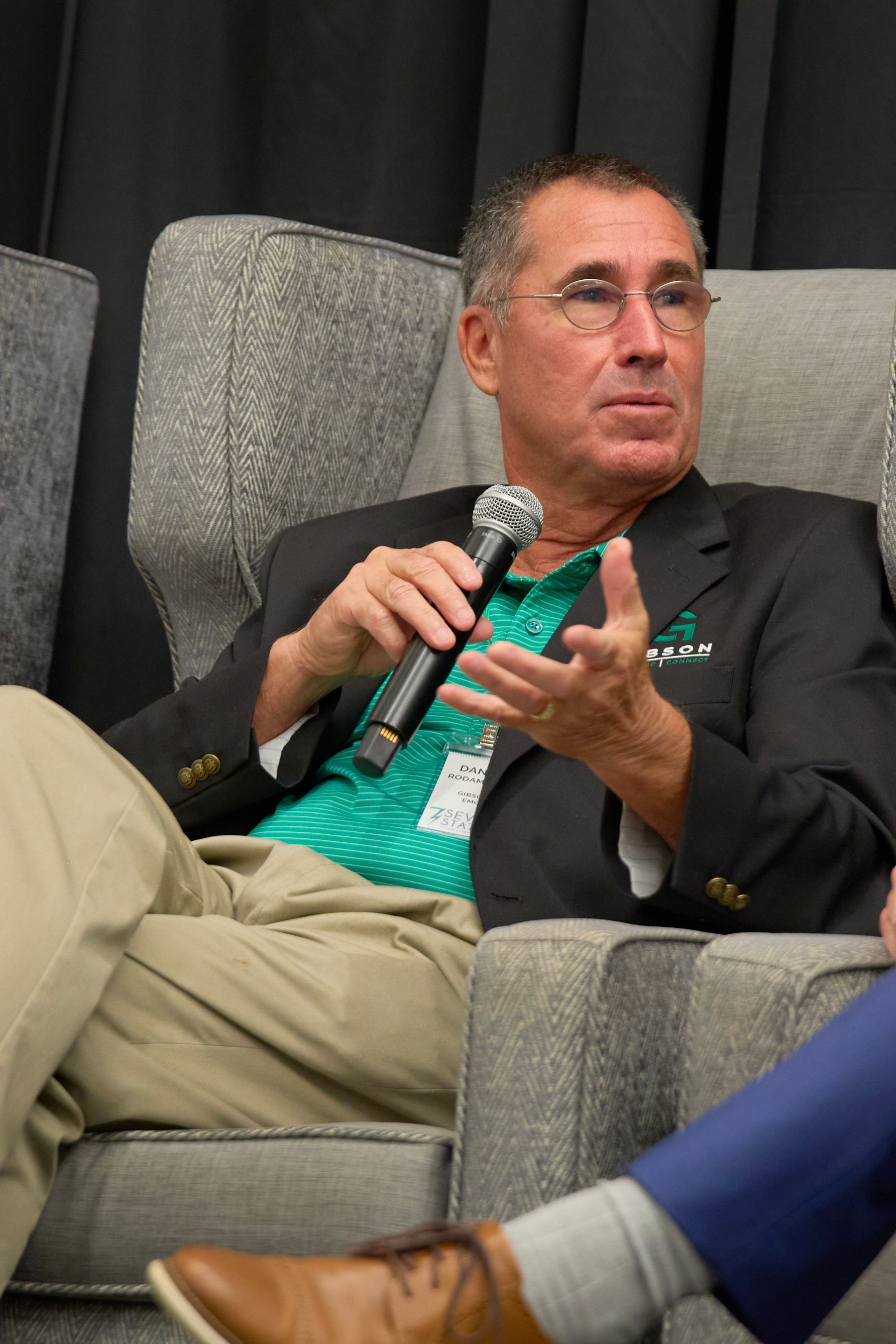 A man is sitting in a chair holding a microphone.