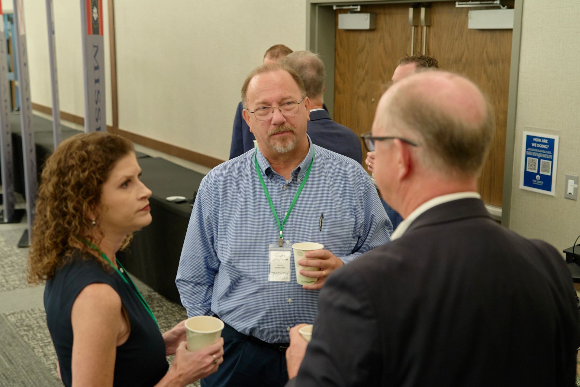 A group of people are standing in a room talking to each other.