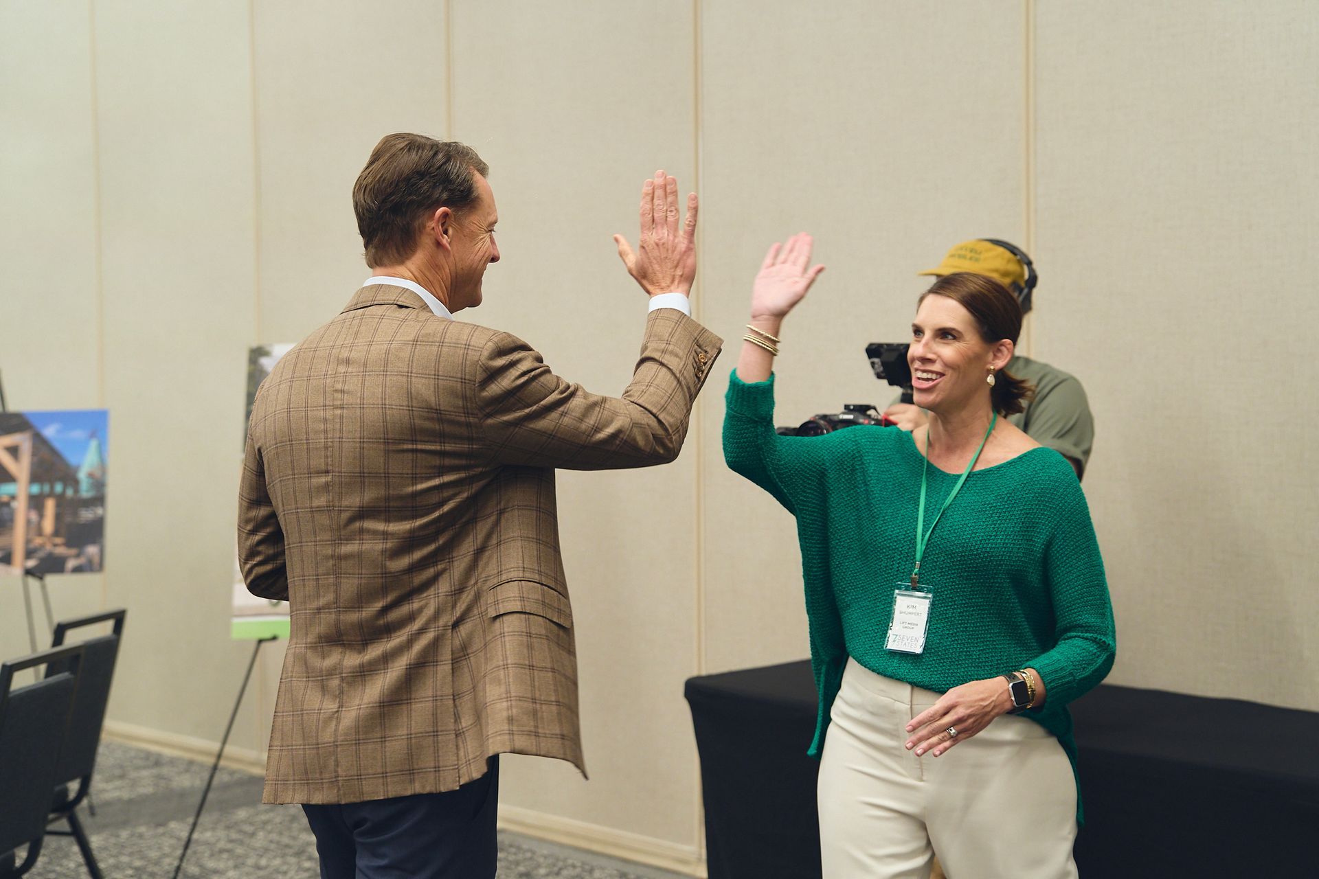 A man and a woman are giving each other a high five in a room.