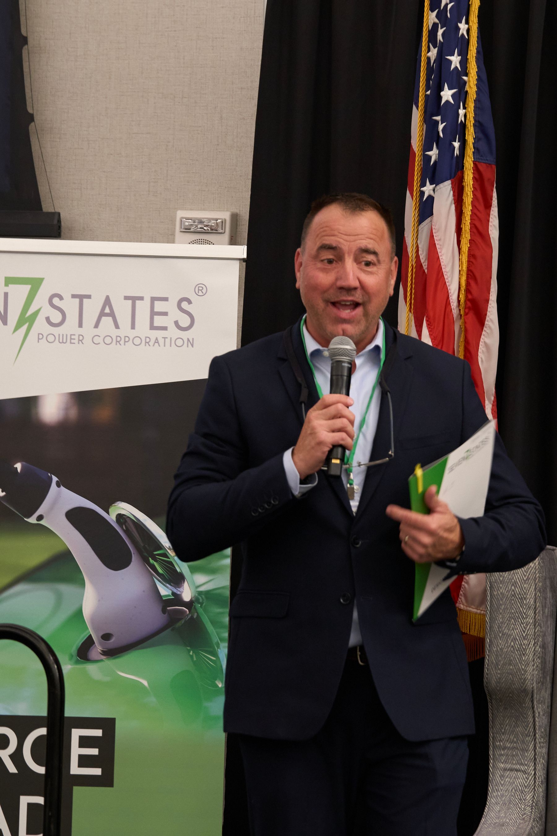 A man in a suit is holding a microphone in front of a sign that says states