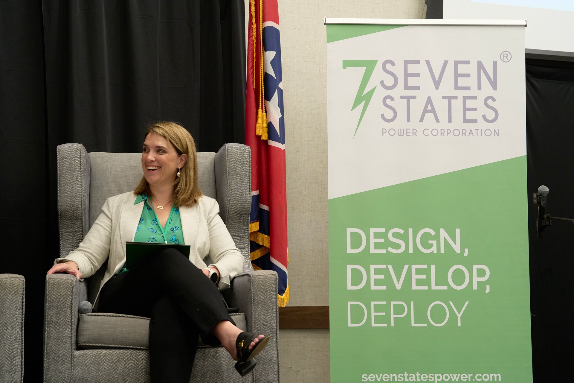 A woman is sitting in a chair in front of a sign that says seven states