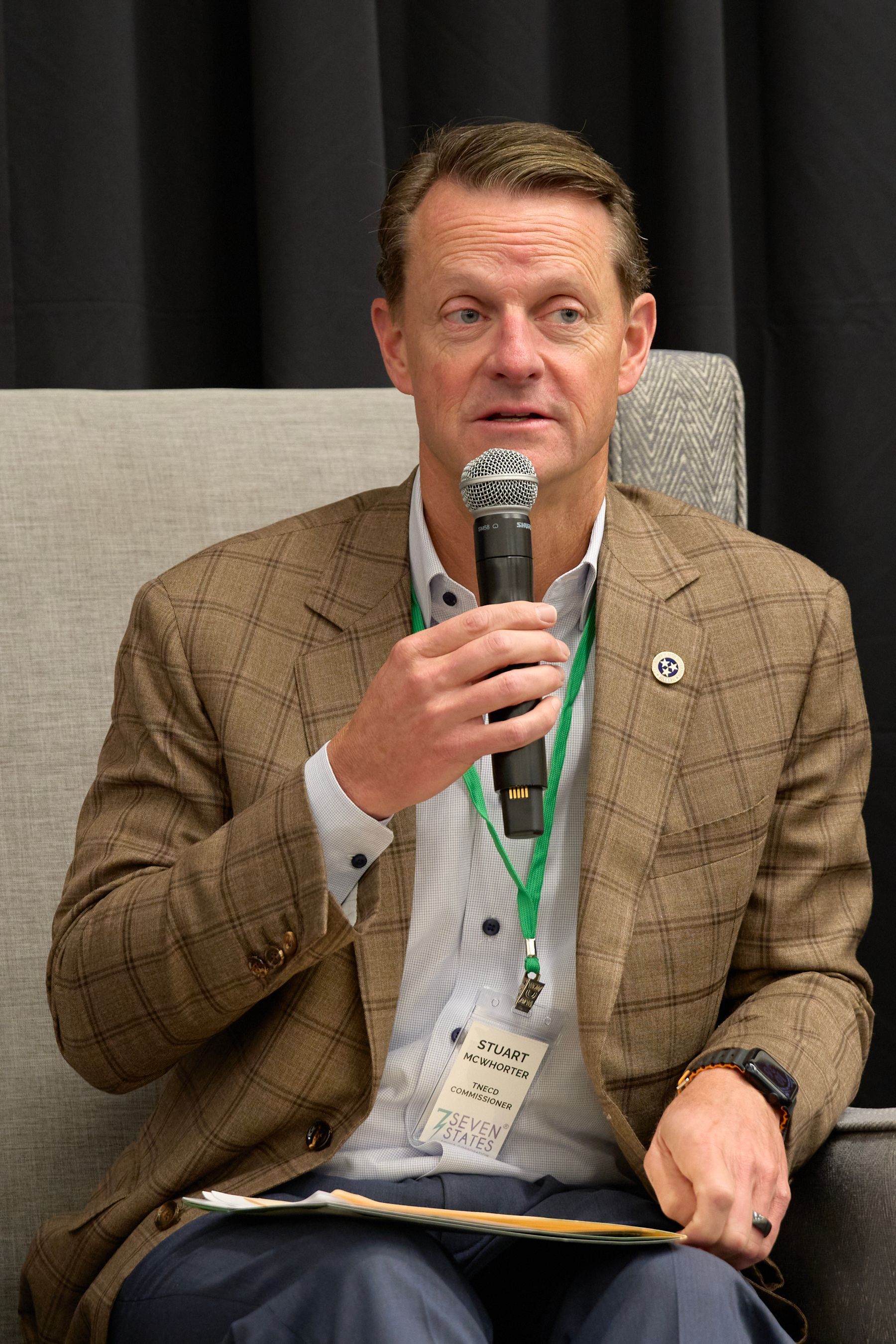 A man is sitting in a chair holding a microphone.