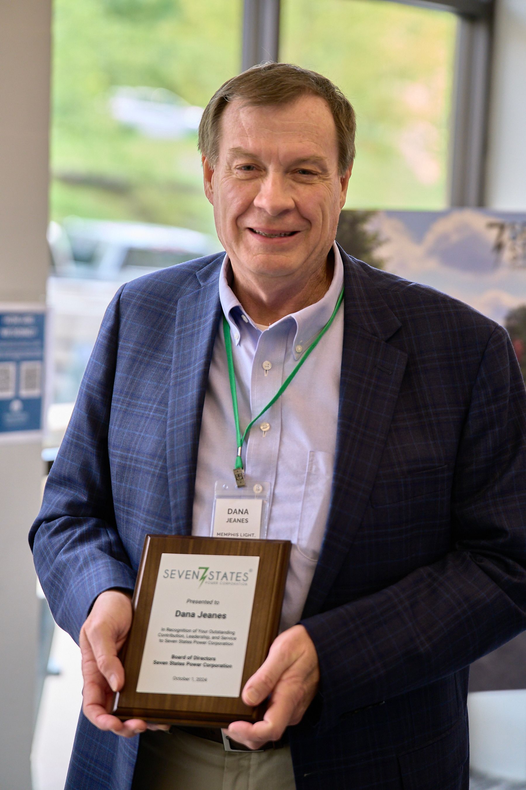 A man in a suit is holding a wooden plaque.