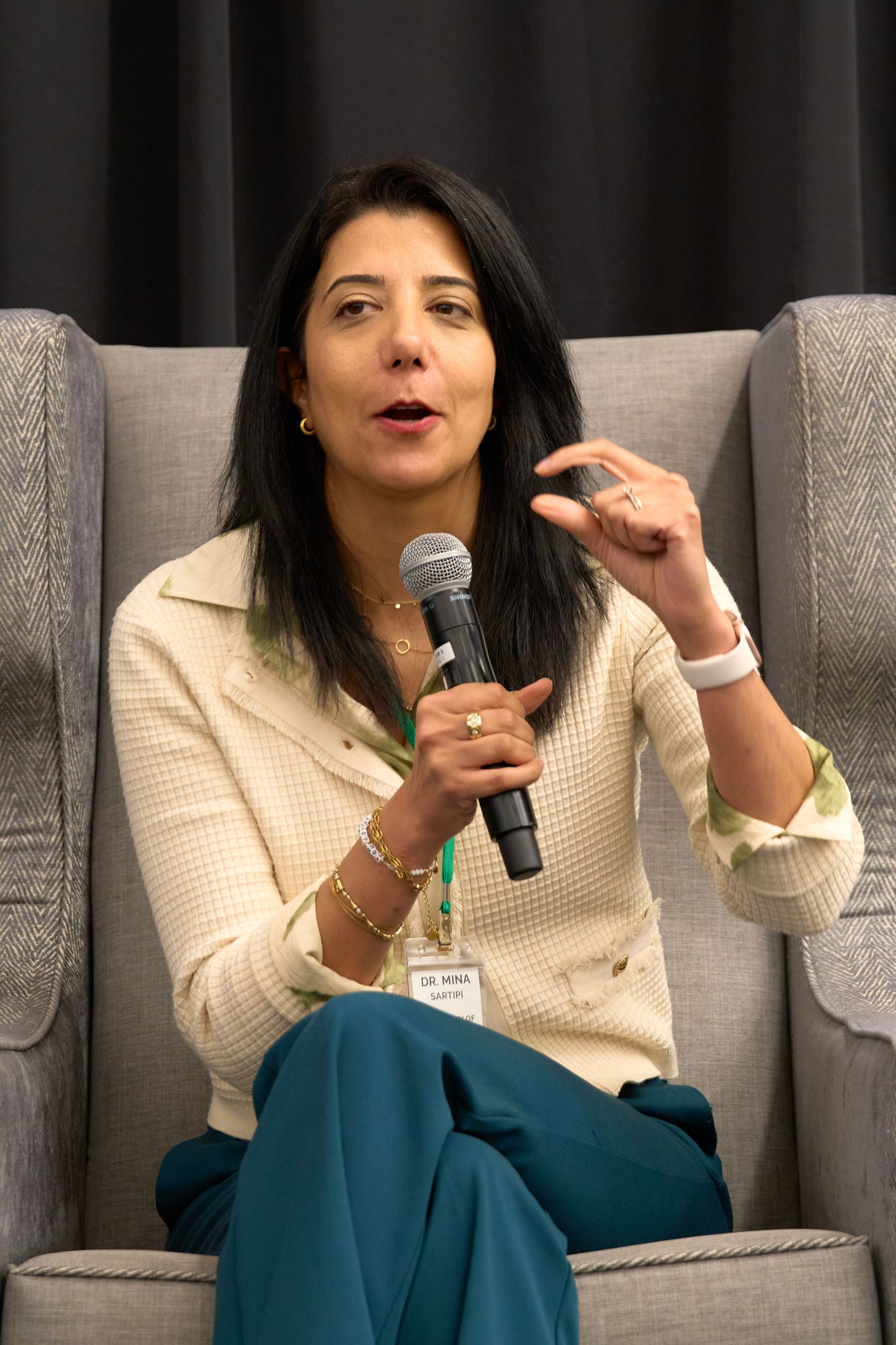 A woman is sitting in a chair holding a microphone.